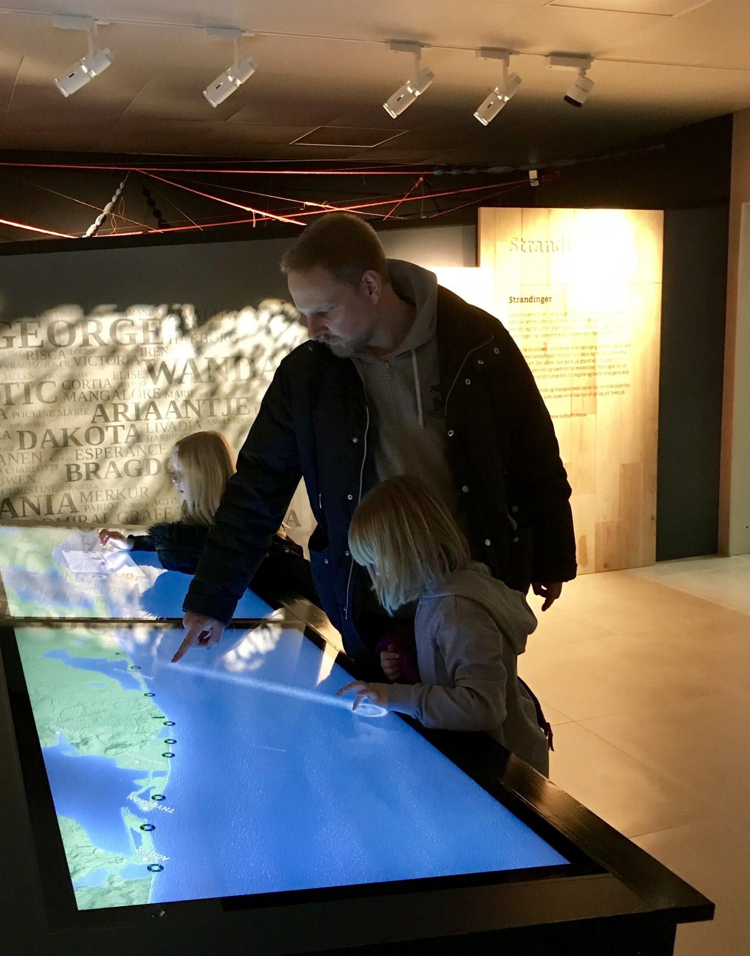 Familie kigger på digital montre på Strandingsmuseet