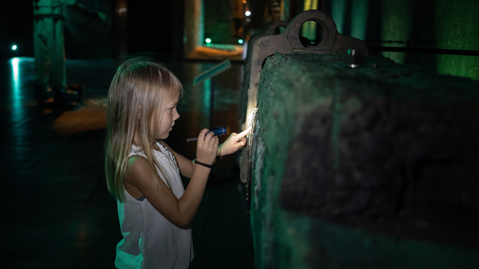 Lille pige går på opdagelse i strandingsmuseets genstande med en lommelygte